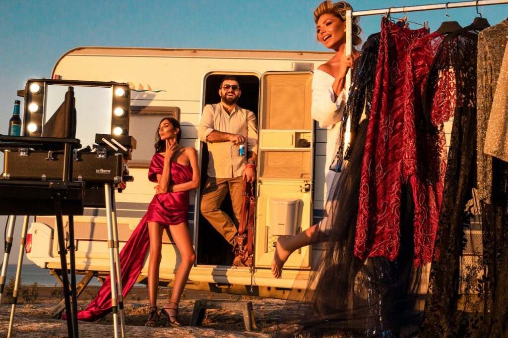 Actors on film set in trailer with costume rack and camera